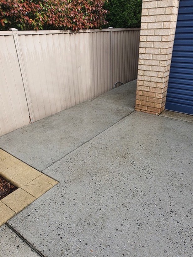 The same path finished, dry and pale, beside the brick pillar and blue roller door