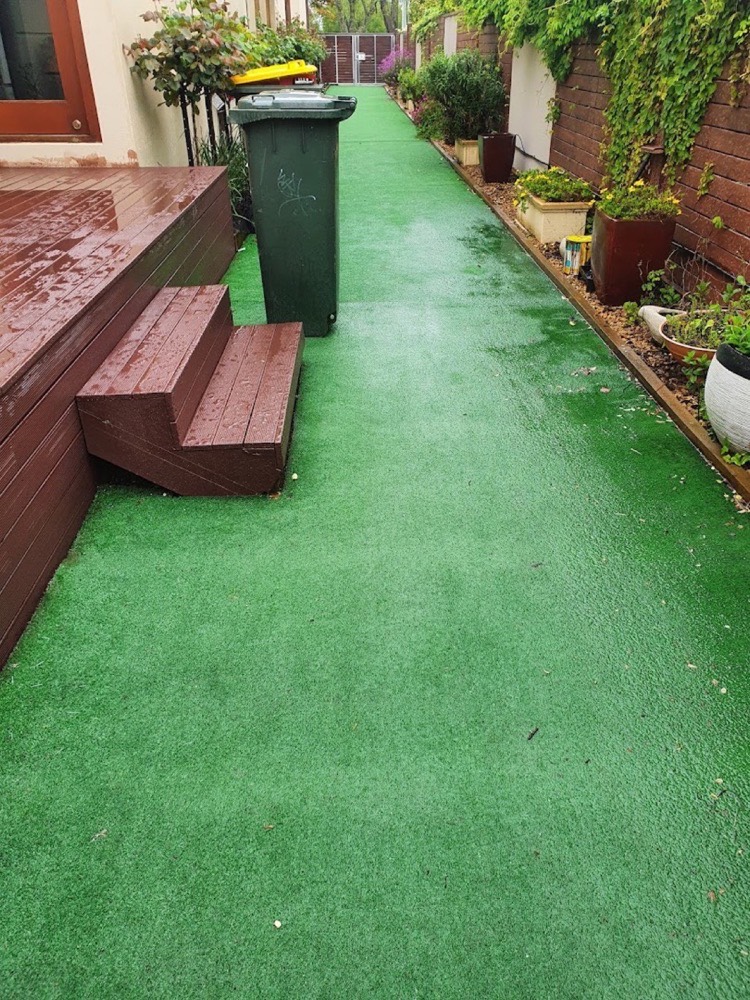 A synthetic grass path cleaned between two garden beds