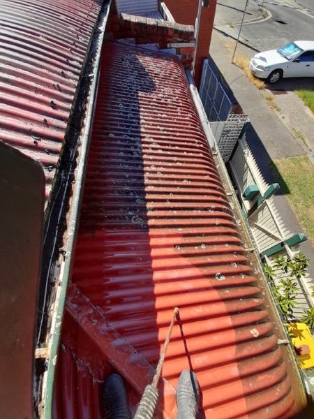 A box gutter beside a red corrugated iron roof, washed out from above