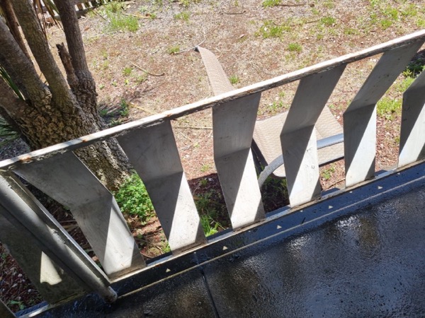 An extension ladder set up over freshly washed paving beside a garden bed