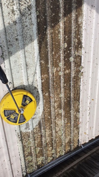 A fence line being cleaned with a rotary surface cleaner